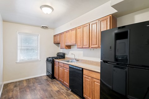 an empty kitchen with black appliances and wooden cabinets